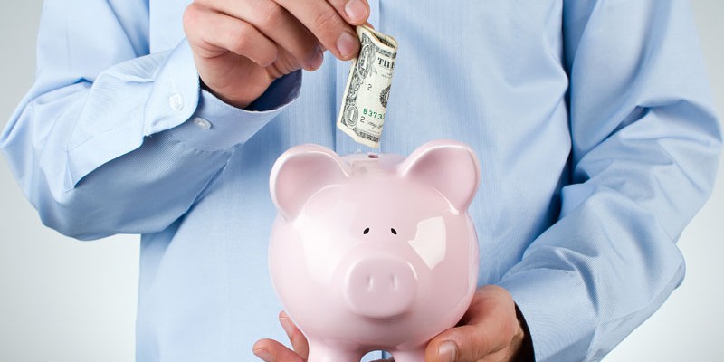 Male hand putting coin into a piggy bank